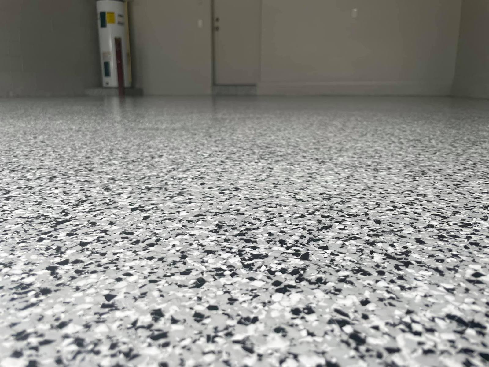 Close up of a gray, white and black flake garage floor coating